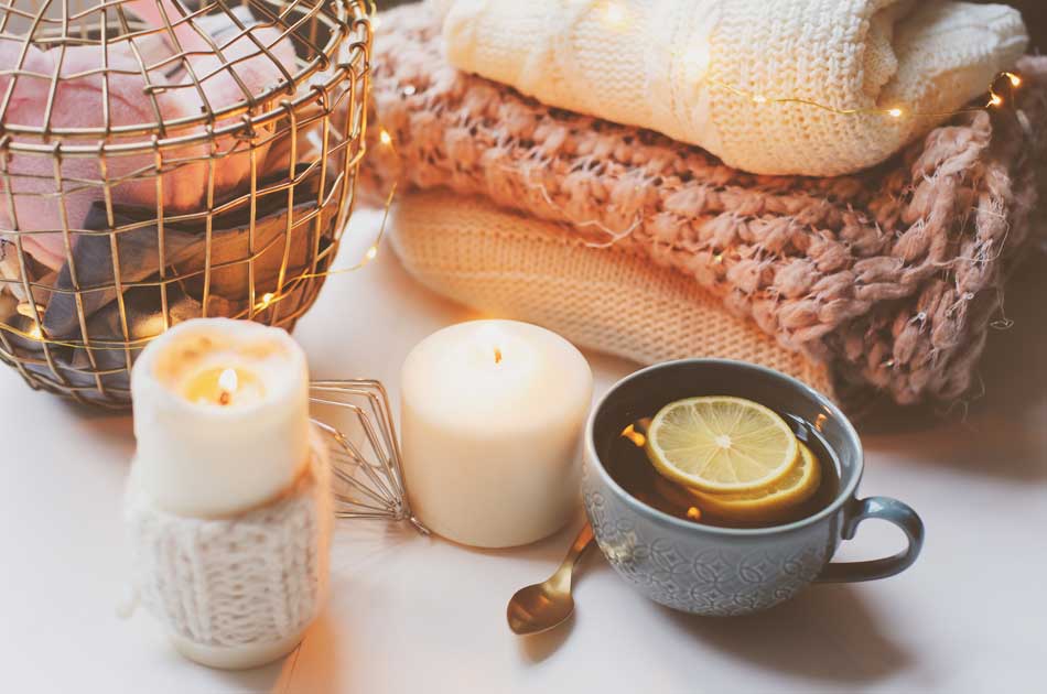 Candles, a warm cup of tea, and knit blankets represent hygge, the Danish art of coziness